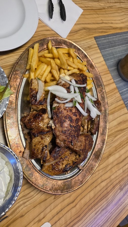 Grillplatte auf Kupferteller mit Pommes und Zwiebeln